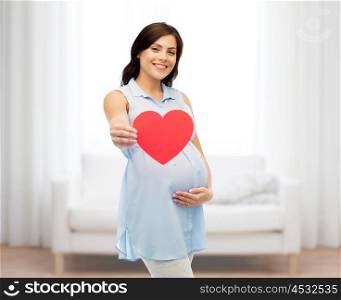 pregnancy, love, people and expectation concept - happy pregnant woman with red heart shape touching her belly over home room background