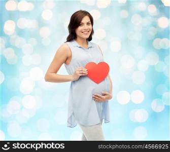 pregnancy, love, people and expectation concept - happy pregnant woman with red heart shape touching her belly over blue holidays lights background