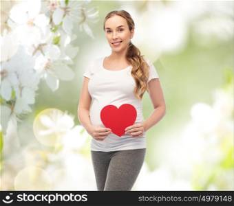 pregnancy, love, people and expectation concept - happy pregnant woman with red heart over natural spring cherry blossom background. happy pregnant woman with red heart