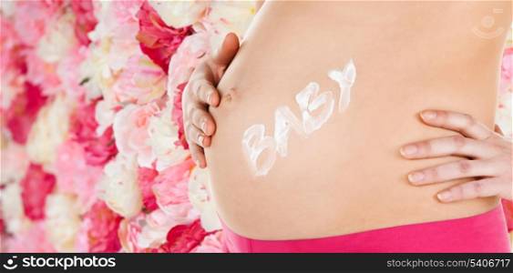 pregnancy, maternity and health concept - belly of a pregnant woman with cream