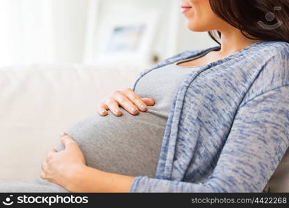 pregnancy, maternity, people and expectation concept - close up of happy pregnant woman with big belly lying on sofa at home