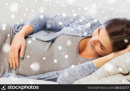 pregnancy, maternity, people, winter and expectation concept - close up of happy pregnant woman with big belly lying on sofa at home over snow