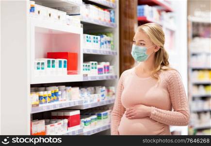 pregnancy, medicine and health concept - pregnant woman wearing protective medical mask for protection from virus disease at pharmacy. pregnant woman in mask with medicines at pharmacy