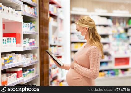 pregnancy, medicine and health concept - pregnant woman wearing protective medical mask for protection from virus disease with tablet pc computer at pharmacy. pregnant woman in mask with tablet pc at pharmacy