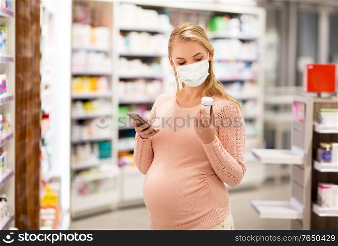 pregnancy, medicine and health concept - pregnant woman wearing protective medical mask for protection from virus disease with smartphone and drug at pharmacy. pregnant woman in mask with medicine at pharmacy