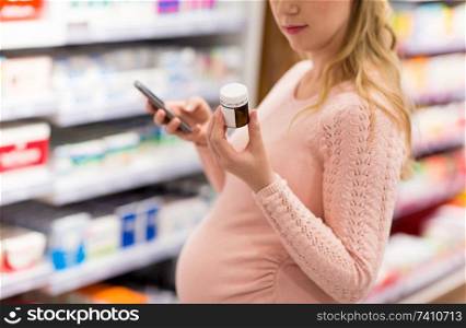 pregnancy, medicine and healthcare concept - close up of pregnant woman with smartphone choosing medication at pharmacy. pregnant woman choosing medicine at pharmacy