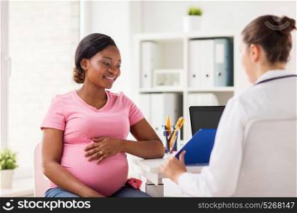 pregnancy, medicine, healthcare and people concept - gynecologist doctor with clipboard and happy pregnant african american woman meeting at hospital. gynecologist and pregnant woman at hospital