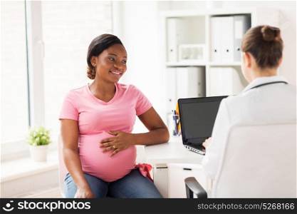 pregnancy, medicine, healthcare and people concept - gynecologist doctor with laptop computer and pregnant african american woman meeting at hospital. doctor with laptop and pregnant woman at clinic