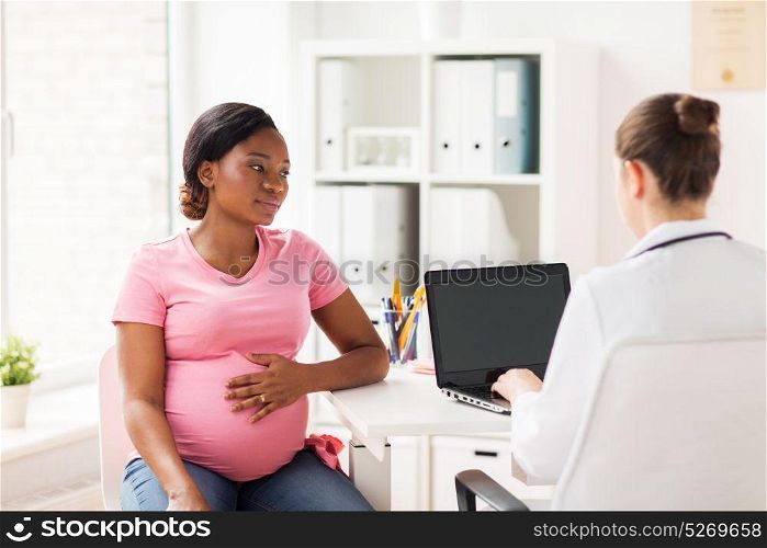pregnancy, medicine, healthcare and people concept - gynecologist doctor with laptop computer and pregnant african american woman meeting at hospital. doctor with laptop and pregnant woman at clinic