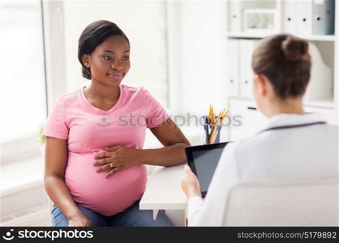 pregnancy, medicine, healthcare and people concept - gynecologist doctor with tablet pc computer and pregnant african american woman meeting at hospital. doctor with tablet pc and pregnant woman at clinic