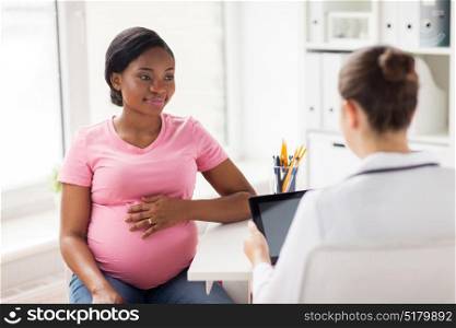 pregnancy, medicine, healthcare and people concept - gynecologist doctor with tablet pc computer and pregnant african american woman meeting at hospital. doctor with tablet pc and pregnant woman at clinic