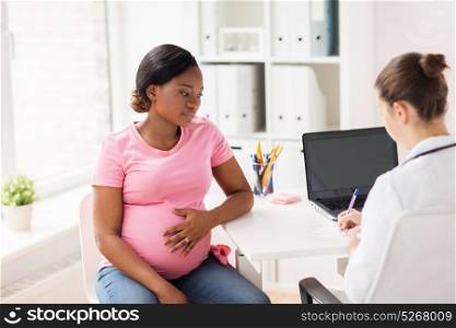 pregnancy, medicine, healthcare and people concept - gynecologist doctor writing prescription and pregnant african american woman at hospital. gynecologist doctor and pregnant woman at hospital