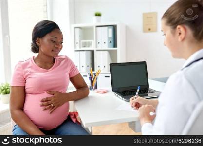 pregnancy, medicine, healthcare and people concept - gynecologist doctor writing prescription and pregnant african american woman at hospital. gynecologist doctor and pregnant woman at hospital