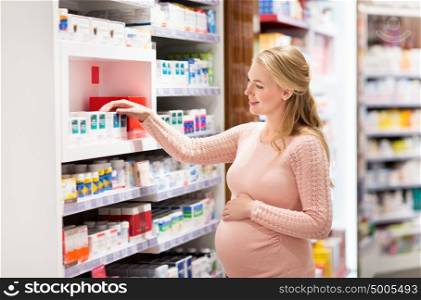 pregnancy, medicine, people, healthcare and expectation concept - happy pregnant woman looking for medication at pharmacy. happy pregnant woman with medication at pharmacy
