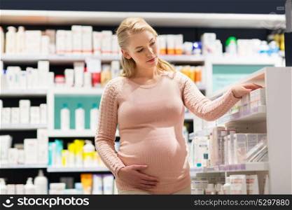 pregnancy, medicine, people, healthcare and expectation concept - happy pregnant woman looking for medication at pharmacy. happy pregnant woman with medication at pharmacy