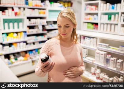 pregnancy, medicine, people, healthcare and expectation concept - happy pregnant woman with medication jar at pharmacy. happy pregnant woman with medication at pharmacy
