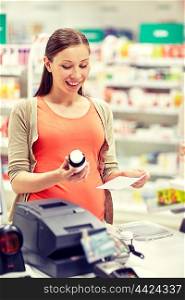 pregnancy, medicine, pharmaceutics, health care and people concept - happy pregnant woman with medication and prescription paper at pharmacy cash register