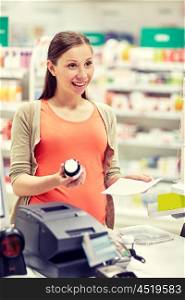 pregnancy, medicine, pharmaceutics, health care and people concept - happy pregnant woman with medication and prescription paper at pharmacy cash register
