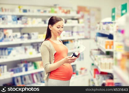 pregnancy, medicine, pharmaceutics, health care and people concept - happy pregnant woman with medication and prescription paper at pharmacy