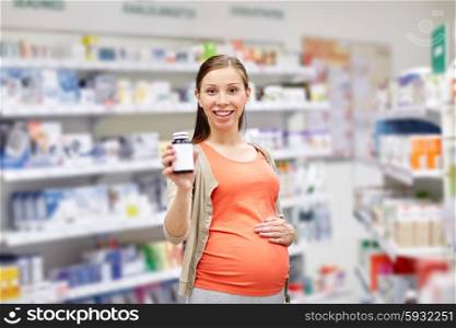 pregnancy, medicine, pharmaceutics, health care and people concept - happy pregnant woman showing medication jar at pharmacy