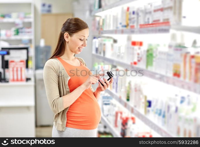 pregnancy, medicine, pharmaceutics, health care and people concept - happy pregnant woman reading label on medication jar at pharmacy