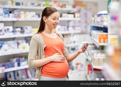 pregnancy, medicine, pharmaceutics, health care and people concept - happy pregnant woman with medication at pharmacy