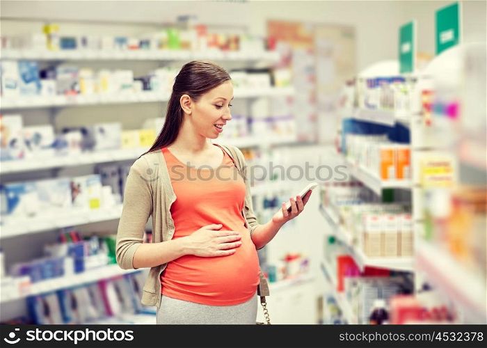 pregnancy, medicine, pharmaceutics, health care and people concept - happy pregnant woman with smartphone at pharmacy