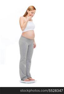 pregnancy, motherhood and happiness concept - amazed pregnant woman weighting herself
