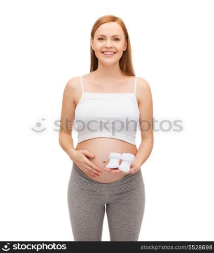 pregnancy, motherhood and happiness concept - happy future mother holding bootees