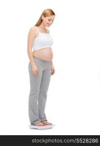pregnancy, motherhood and happiness concept - happy pregnant woman weighting herself