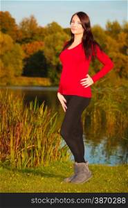 Pregnancy, motherhood and happiness concept. Relaxed calm pregnant woman walking outside in autumn park