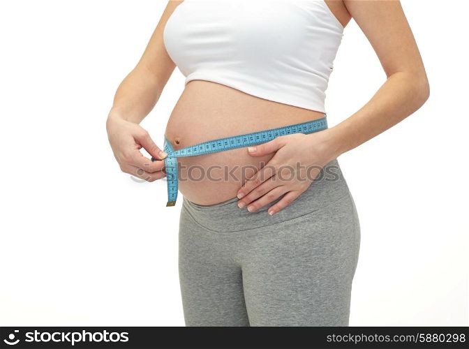 pregnancy, motherhood, control, people and expectation concept - close up of happy pregnant woman measuring her bare tummy