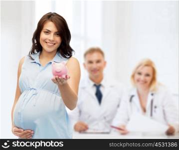 pregnancy, motherhood, finance and people concept - happy pregnant woman with piggybank over medics at maternity hospital background