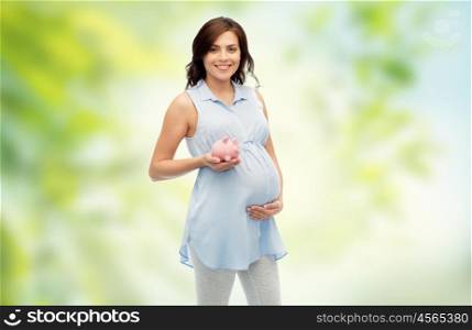 pregnancy, motherhood, finance, saving and people concept - happy pregnant woman with piggybank over green natural background
