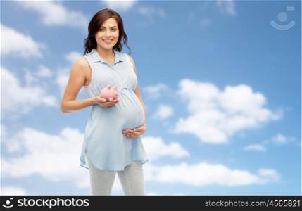 pregnancy, motherhood, finance, saving and people concept - happy pregnant woman with piggybank over blue sky and clouds background