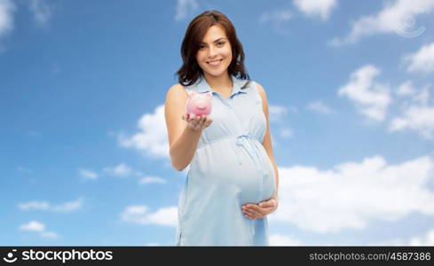 pregnancy, motherhood, finance, saving and people concept - happy pregnant woman with piggybank over blue sky background