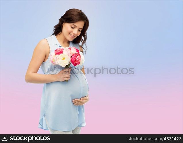 pregnancy, motherhood, holidays, people and expectation concept - happy pregnant woman with flowers touching her big belly over rose quartz and serenity gradient background