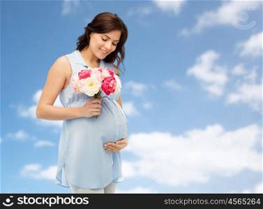 pregnancy, motherhood, holidays, people and expectation concept - happy pregnant woman with flowers touching her big belly over blue sky and clouds background
