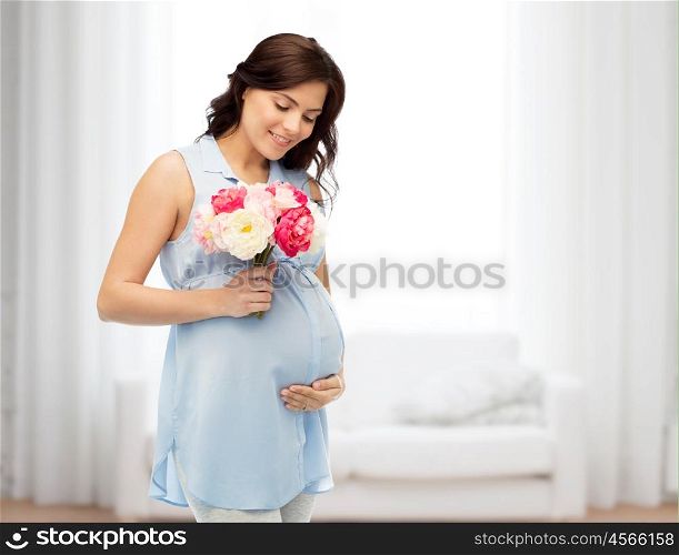 pregnancy, motherhood, holidays, people and expectation concept - happy pregnant woman with flowers touching her big belly over home room background