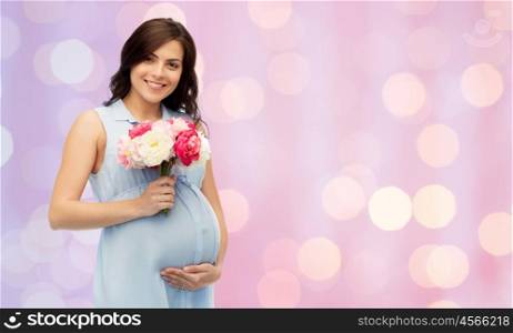 pregnancy, motherhood, holidays, people and expectation concept - happy pregnant woman with flowers touching her big belly over rose quartz and serenity holidays lights background
