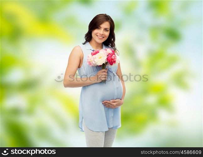 pregnancy, motherhood, holidays, people and expectation concept - happy pregnant woman with flowers touching her big belly over green natural background