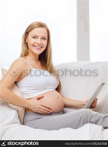 pregnancy, motherhood, internet and technology concept - smiling pregnant woman sitting on sofa with tablet pc computer