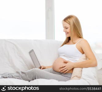 pregnancy, motherhood, internet and technology concept - smiling pregnant woman sitting on sofa with tablet pc computer