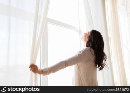 pregnancy, motherhood, people and expectation concept - close up of happy pregnant woman opening window curtains