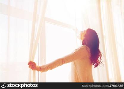 pregnancy, motherhood, people and expectation concept - close up of happy pregnant woman opening window curtains