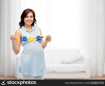 pregnancy, motherhood, people and expectation concept - happy pregnant woman holding rattle toy over home living room background