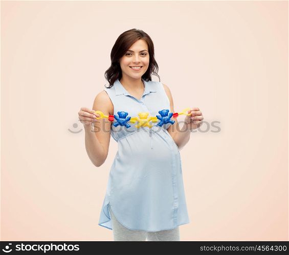 pregnancy, motherhood, people and expectation concept - happy pregnant woman holding rattle toy over beige background
