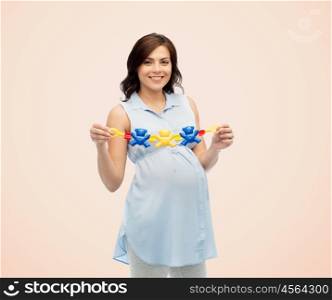 pregnancy, motherhood, people and expectation concept - happy pregnant woman holding rattle toy over beige background