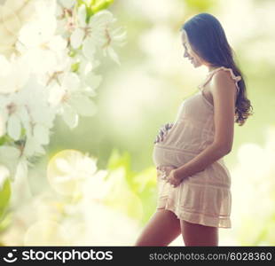 pregnancy, motherhood, people and expectation concept - happy pregnant woman in chemise over green background with flowers