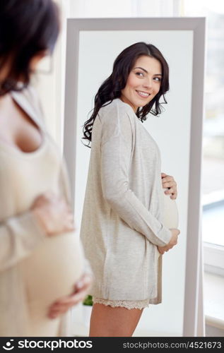 pregnancy, motherhood, people and expectation concept - happy pregnant woman looking to mirror at home